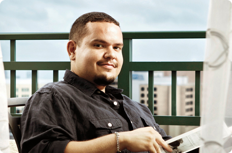 Young man, living with factor XIII A-subunit deficiency, seated on an outdoor balcony while reading